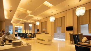 Un moderno vestíbulo de hotel con zona de buffet, arreglos de asientos y una recepción.