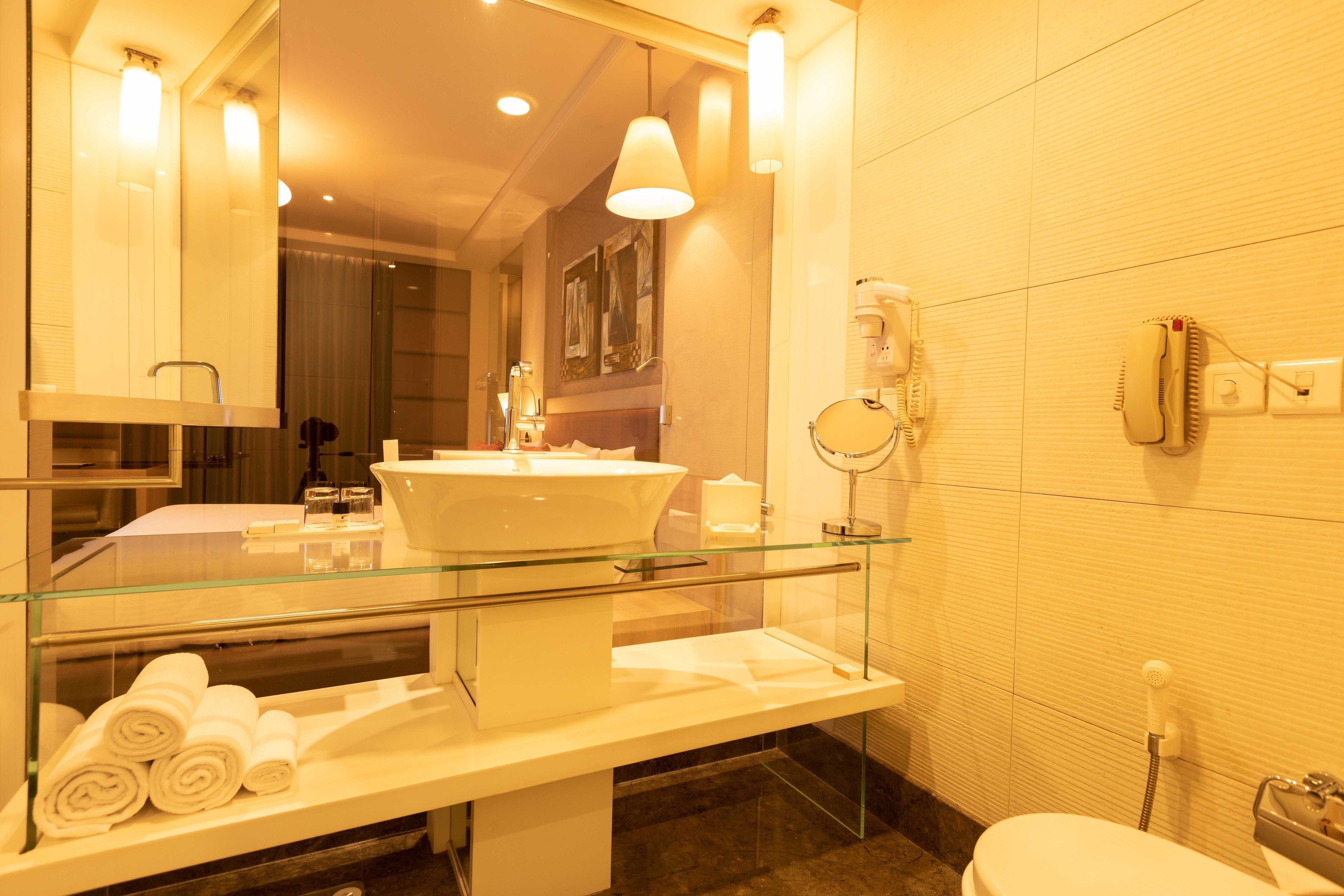 Un baño moderno con lavamanos con cerramiento de vidrio, inodoro y zona de ducha.