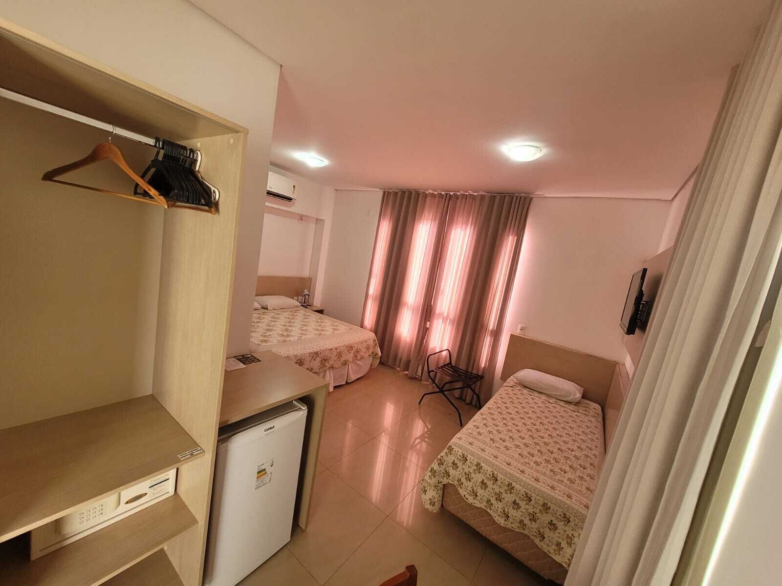 A hotel room with two beds, a desk, a mini fridge, and a wardrobe.