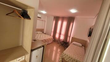 Una habitación de hotel con dos camas, un escritorio, un refrigerador pequeño y un armario.