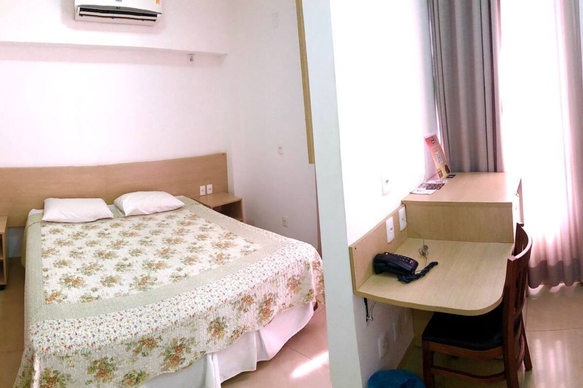 Un dormitorio con cama, mesita de noche y escritorio con silla.