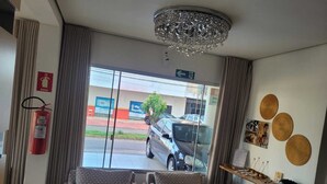 A hotel lobby with a chandelier, two patterned sofas, a fire extinguisher, and a view of the street outside. - Jalapão Hotel (Palmas)