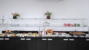 A buffet setup with various food items and a glass display case. - Jalapão Hotel (Palmas)