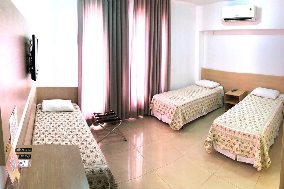 Habitación de hotel con dos camas individuales, un escritorio, una silla y un equipo de aire acondicionado.