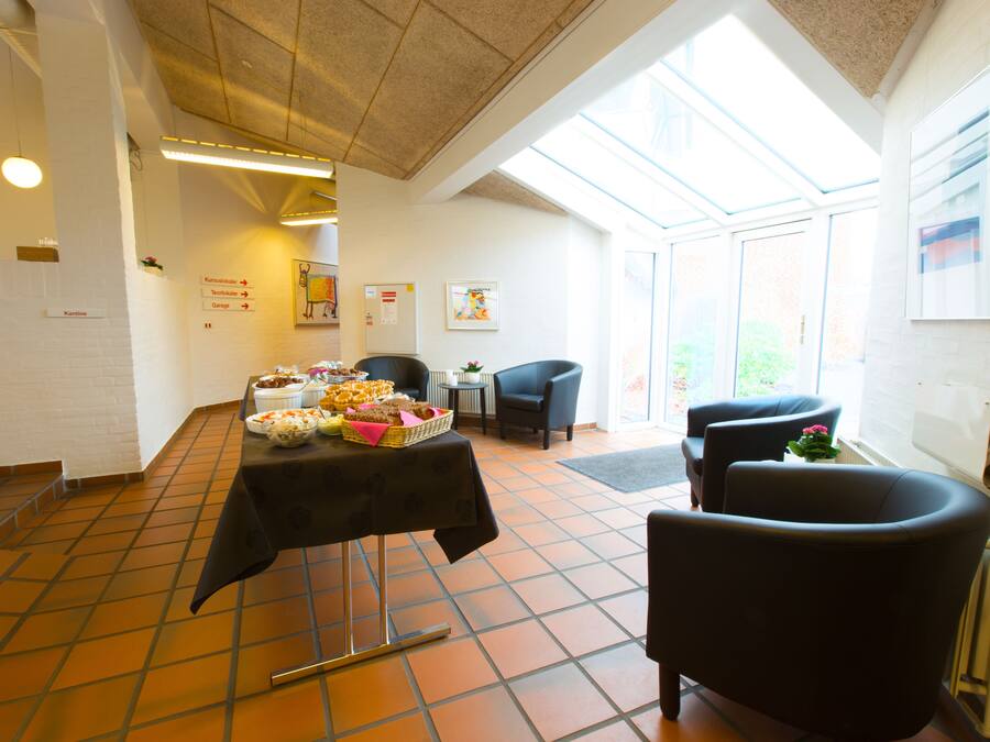 A dining area with a table set for a meal, chairs, and a view through large windows.
