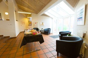 A dining area with a table set for a meal, chairs, and a view through large windows.