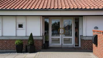 A building with a tiled roof, a glass door entrance, and two potted plants.