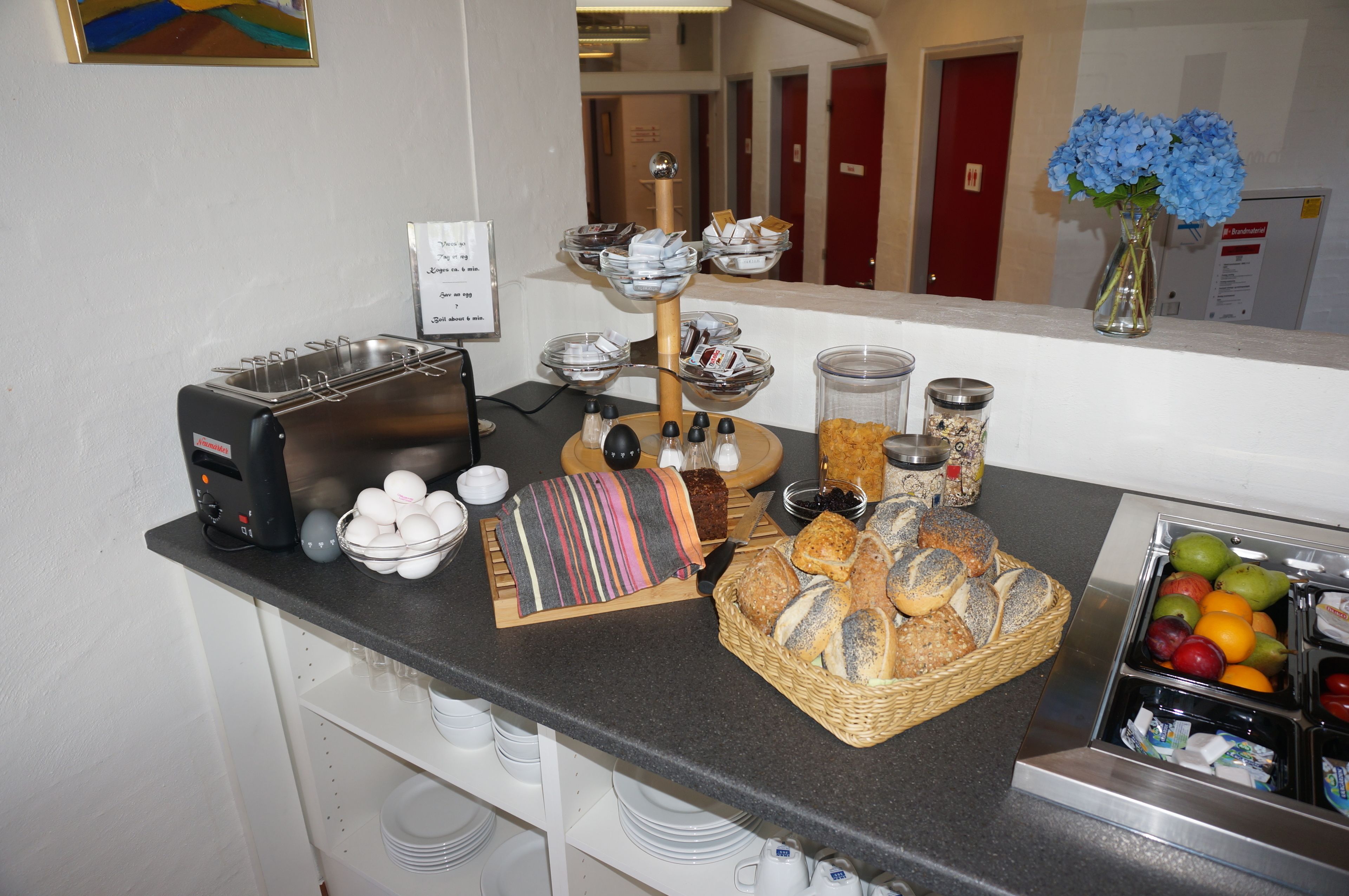 Een ontbijtbuffet met brood, gebak en een fruitschaal.