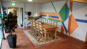 A conference room with a wooden table and chairs, a potted plant, and a colorful geometric wall design.