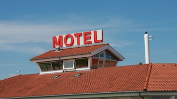 A motel with a red-tiled roof and a prominent 'MOTEL' sign.