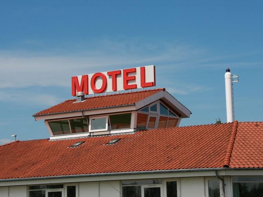A motel with a red-tiled roof and a prominent 'MOTEL' sign.