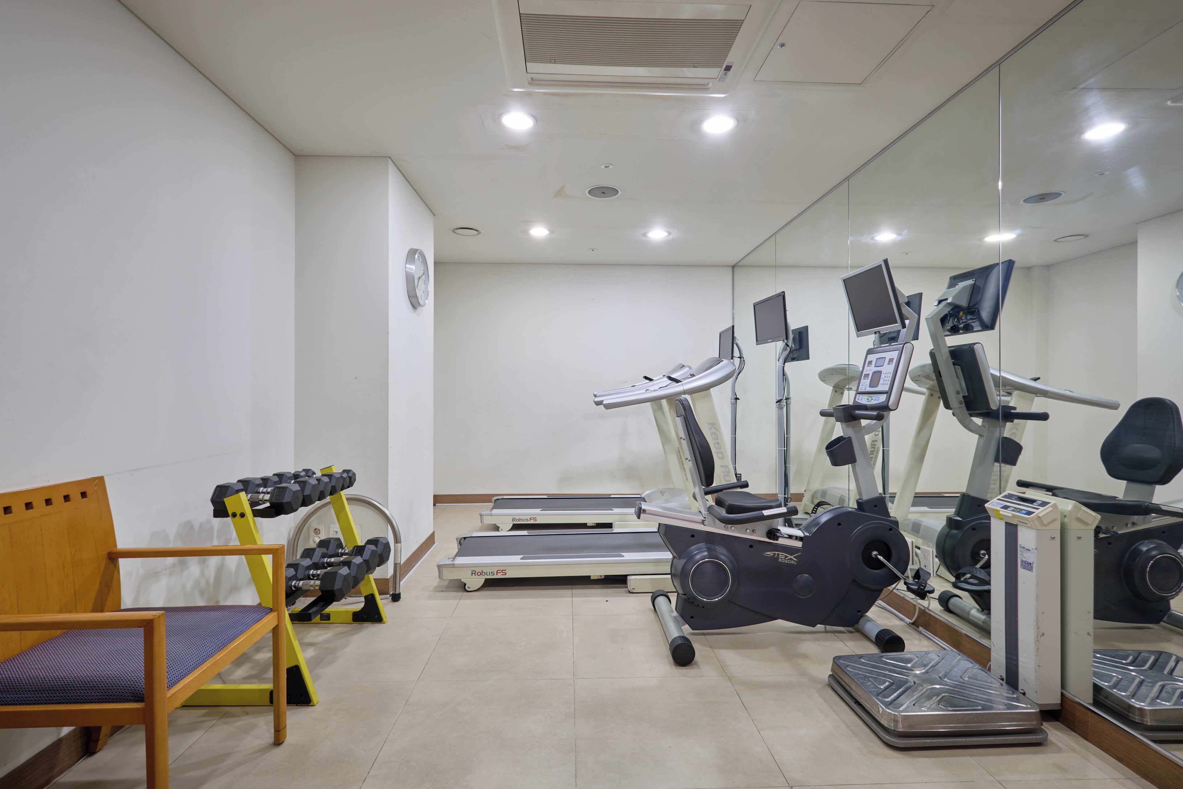 A fitness room with treadmills, a stationary bike, and a weight bench.