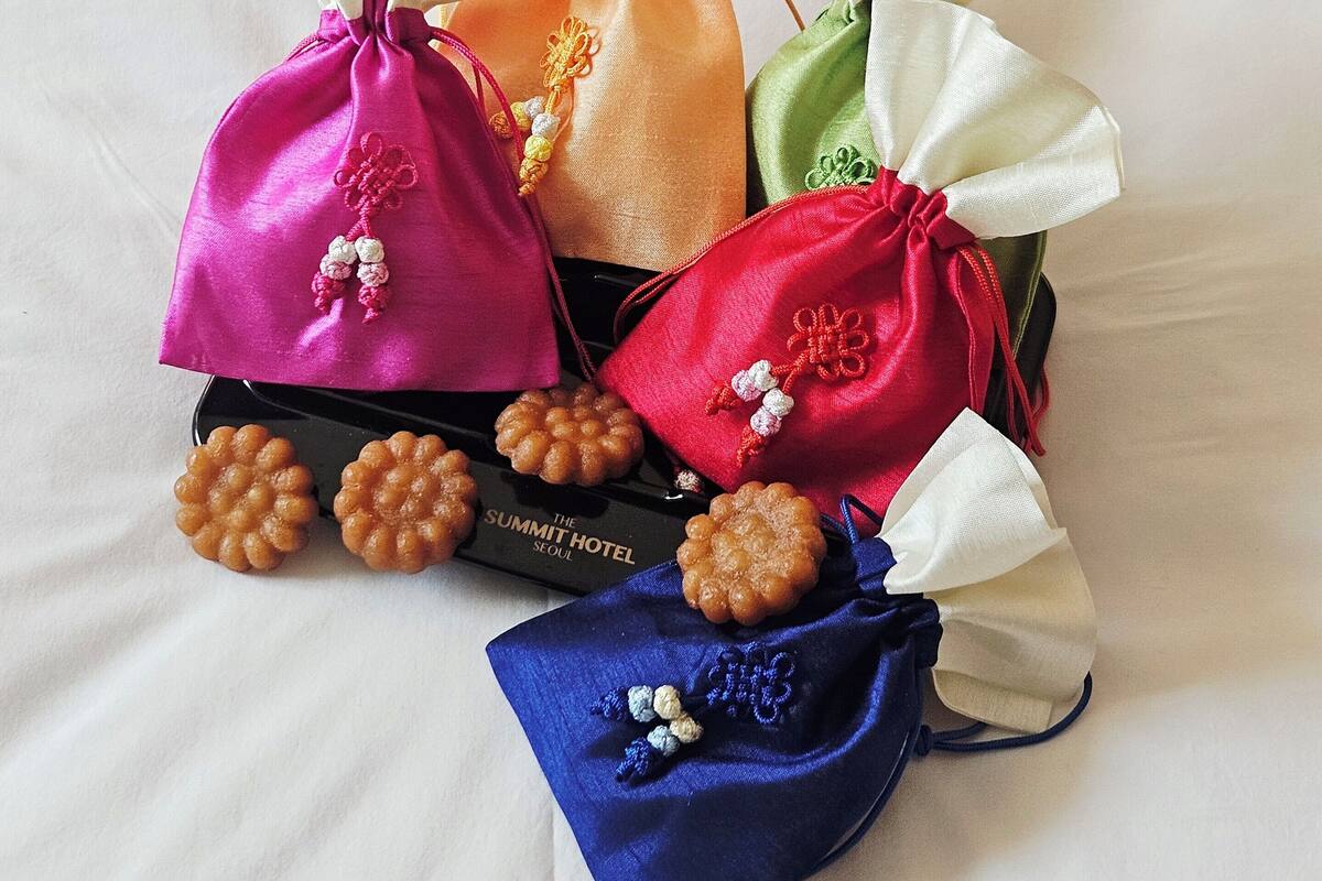 Une collection de sacs-cadeaux colorés ornés de motifs brodés, disposés sur une surface blanche.
