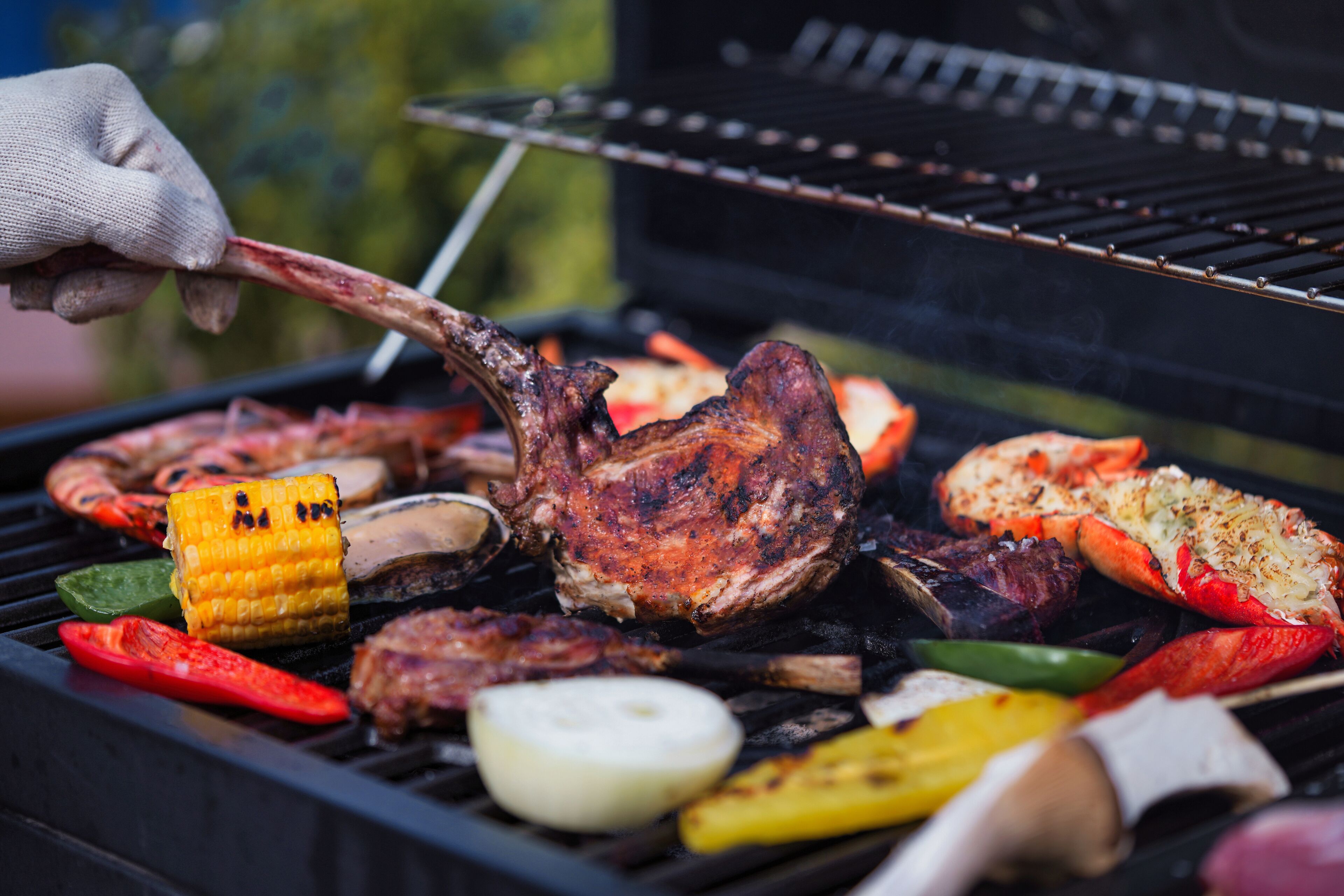 A grill with various meats and vegetables being cooked.