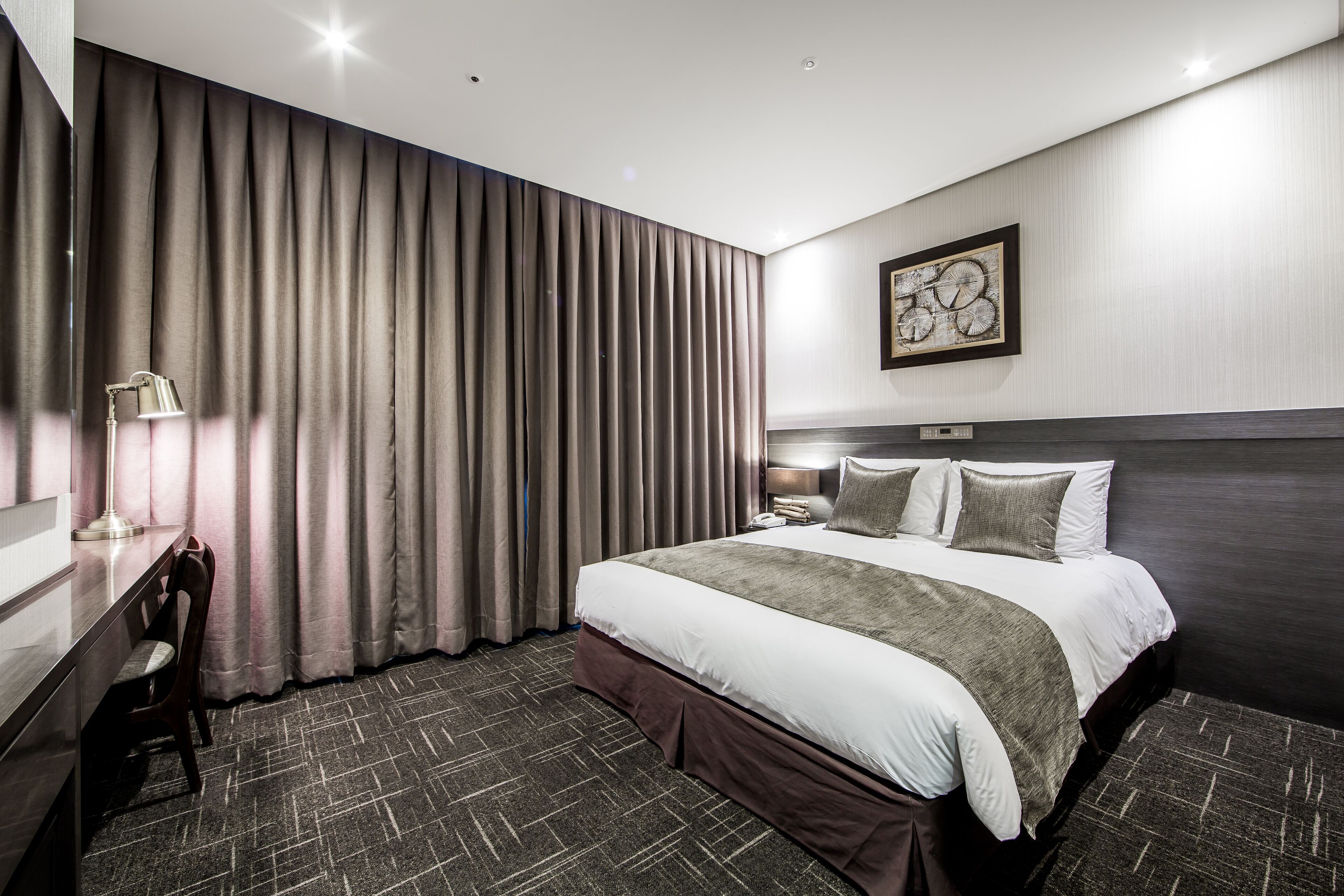 Una habitación de hotel moderna con una cama grande, un escritorio y una silla.
