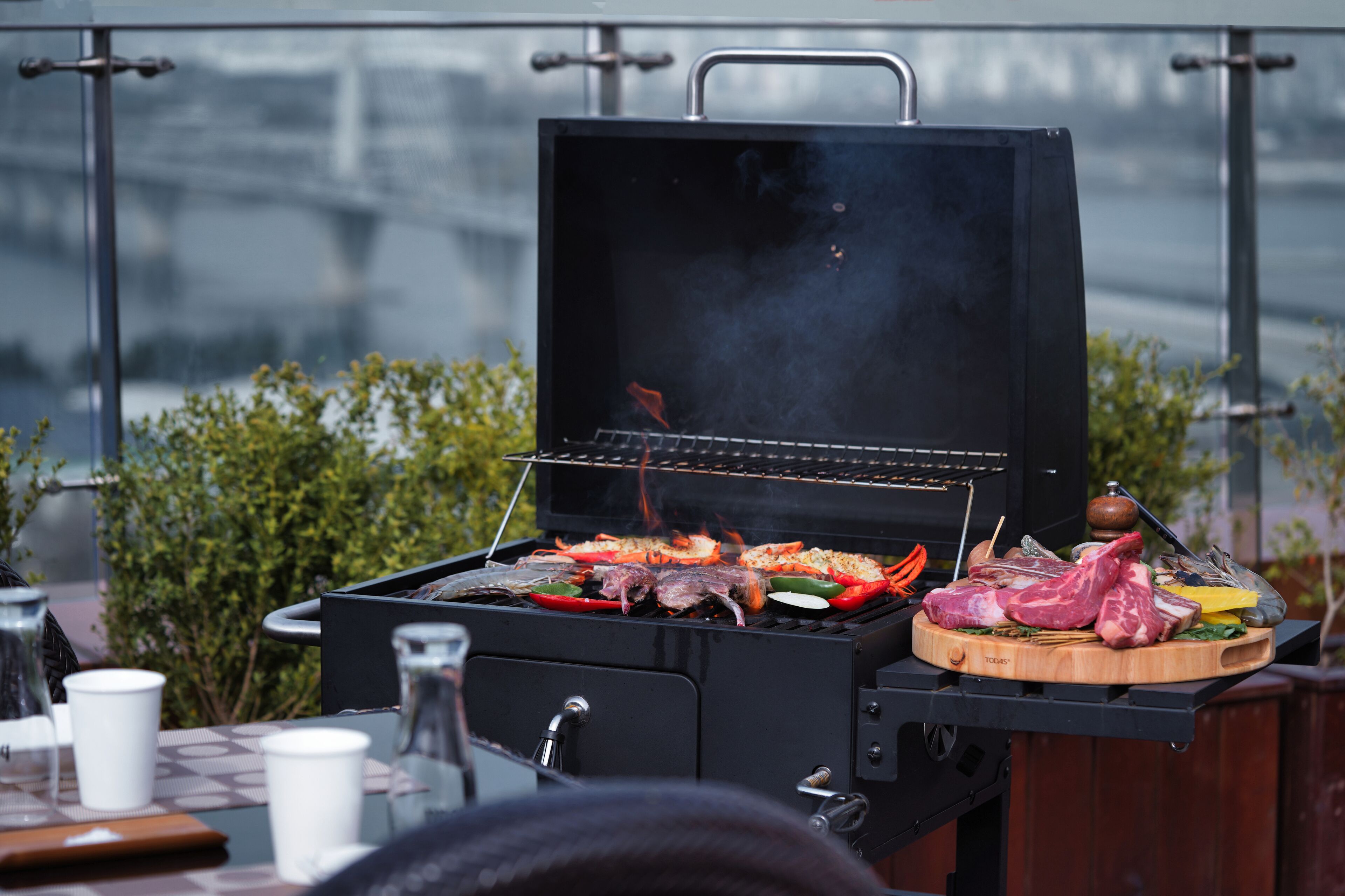 A barbecue grill with various meats and vegetables being cooked.