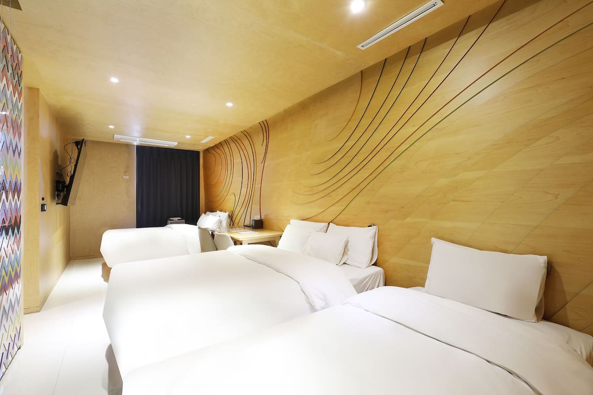 Habitación de hotel con dos camas, un escritorio, una silla y una pared con un diseño único.