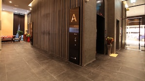 A modern hotel lobby with a reception desk, a seating area with a sofa, and a potted plant. - Hotel The Designers Jongno (Seoul)