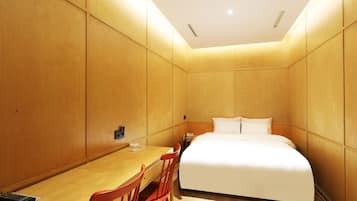 A hotel room with a bed, a desk, and a chair.