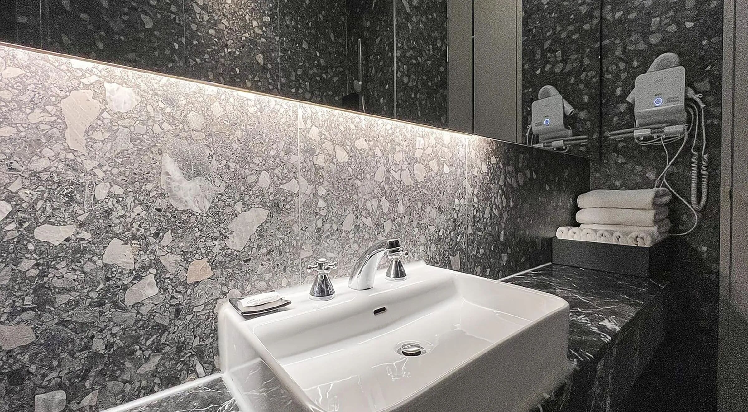 A bathroom with a sink, mirror, and towel rack.