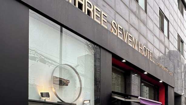 Das Hotel Three Seven mit moderner Fassade, großen Fenstern und einem gut sichtbaren Eingang.
