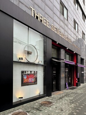 The exterior of the Three Seven Hotel with a modern facade, large windows, and a visible entrance. - Three Seven Hotel (Seoul)