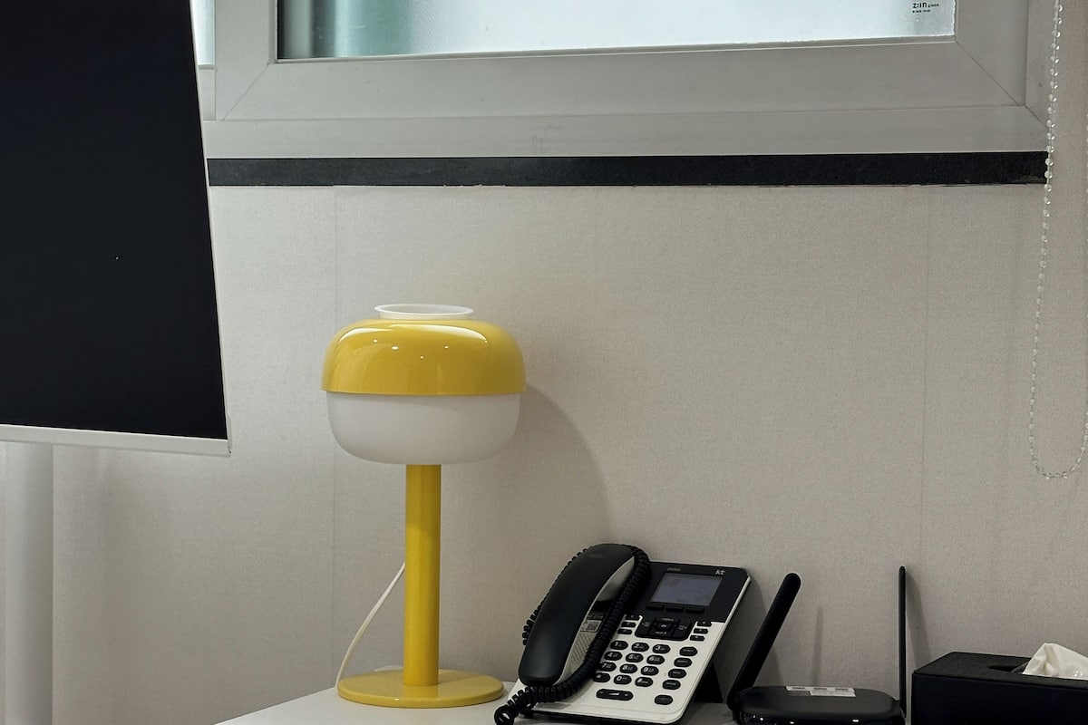 A desk with a telephone, a lamp, and a box with tissues.