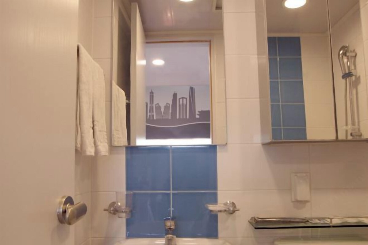 A bathroom with a sink, mirror, and shower.