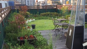 Een dakbalkon met houten terras, barbecue en zitgedeelte.