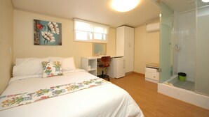 Een slaapkamer met een bed, een bureau, een stoel, een kledingkast en een douchehoek.