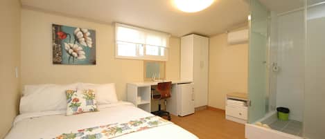 Camera da letto con un letto, una scrivania, una sedia, un armadio e un angolo doccia.