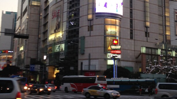Un edificio de hotel Lotte con fachada de vidrio curvo, varios pisos y un llamativo letrero 'Lotte'.