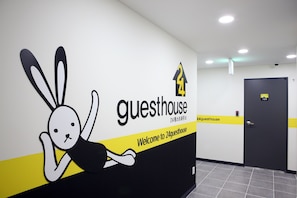 Pared con un conejo caricaturesco y el texto "guesthouse" y "Bienvenido a 24guesthouse".