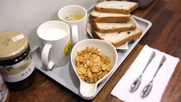 Una bandeja con un tazón de cereal, dos tazas, rebanadas de pan y un frasco de mermelada.