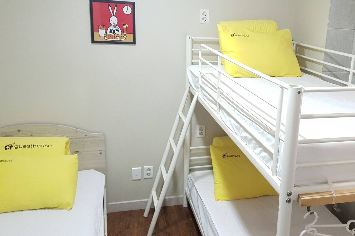 Una cama litera con almohadas amarillas y una mesita con una almohada amarilla.