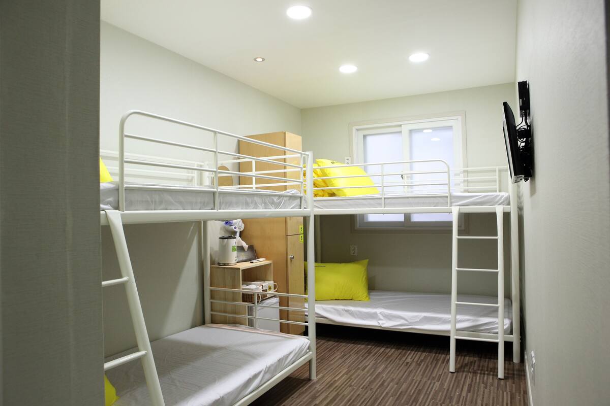 Habitación con literas, un escritorio y una silla, con ventana.