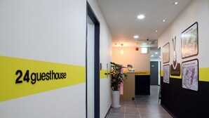 Un pasillo con un letrero que dice "24 guesthouse" y un mostrador de recepción.