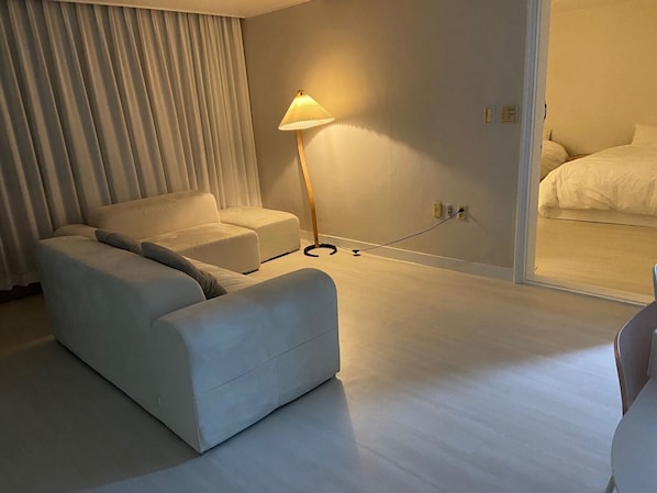 Una habitación de hotel moderna con sofá, lámpara de pie y cama.