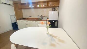 A kitchen with a white table, wooden cabinets, a sink, and a refrigerator.