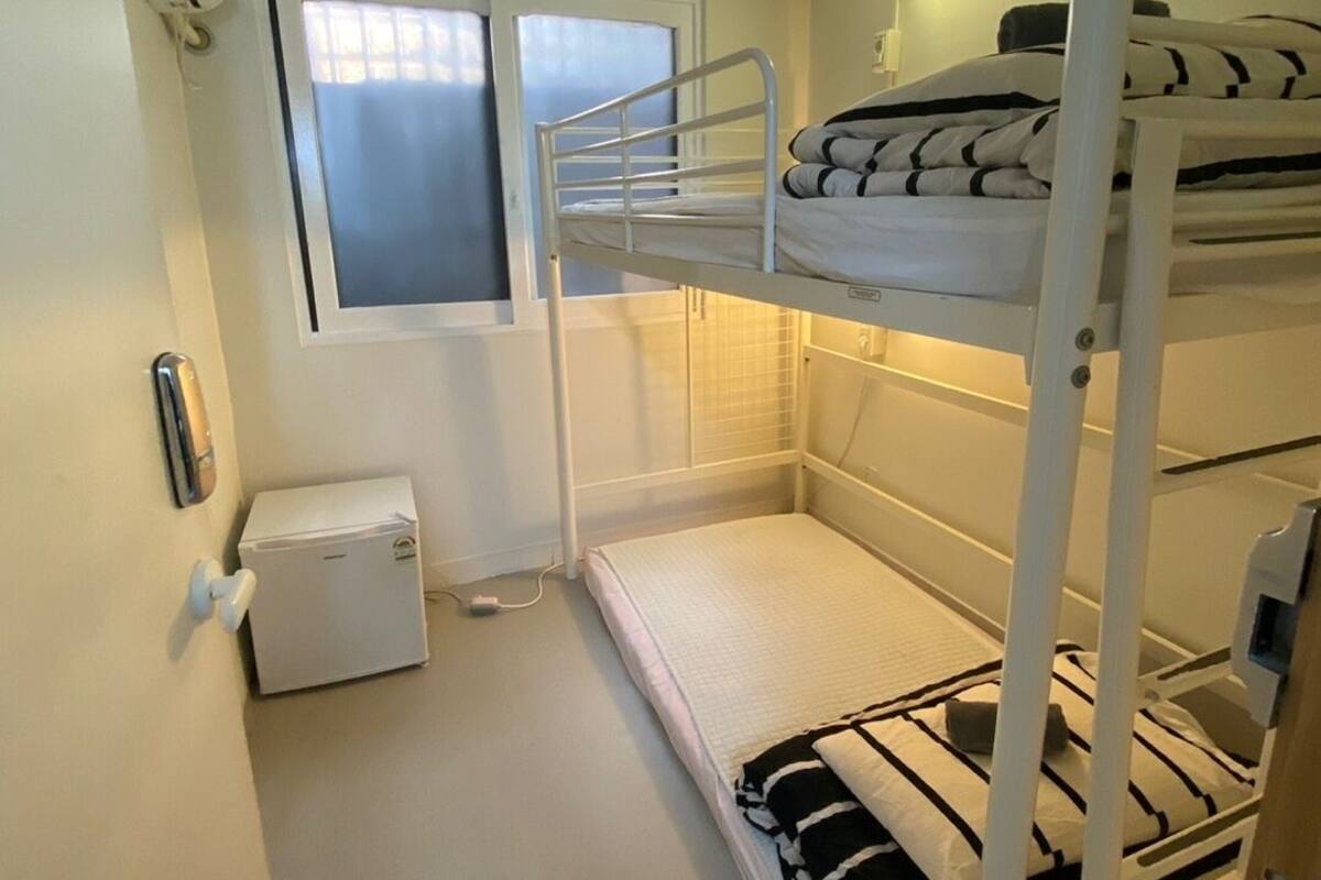 A bunk bed room with a small window, a heater, and a wall-mounted phone.