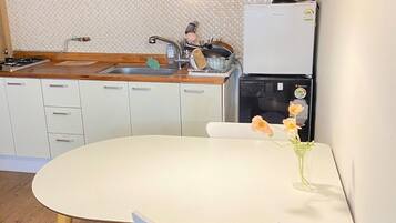 Una cocina compacta con una mesa redonda para comer, armarios de madera, horno empotrado y refrigerador.