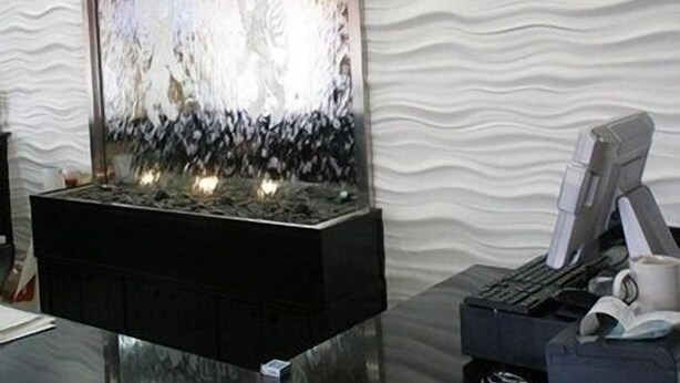 A modern indoor water feature with a reflective surface, placed on a black base.