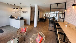 A modern hotel lobby with a reception desk, wicker chairs, wooden tables, and a large mirror reflecting the interior. - Tierra Gaucha Hotel Boutique (San Carlos de Bariloche)