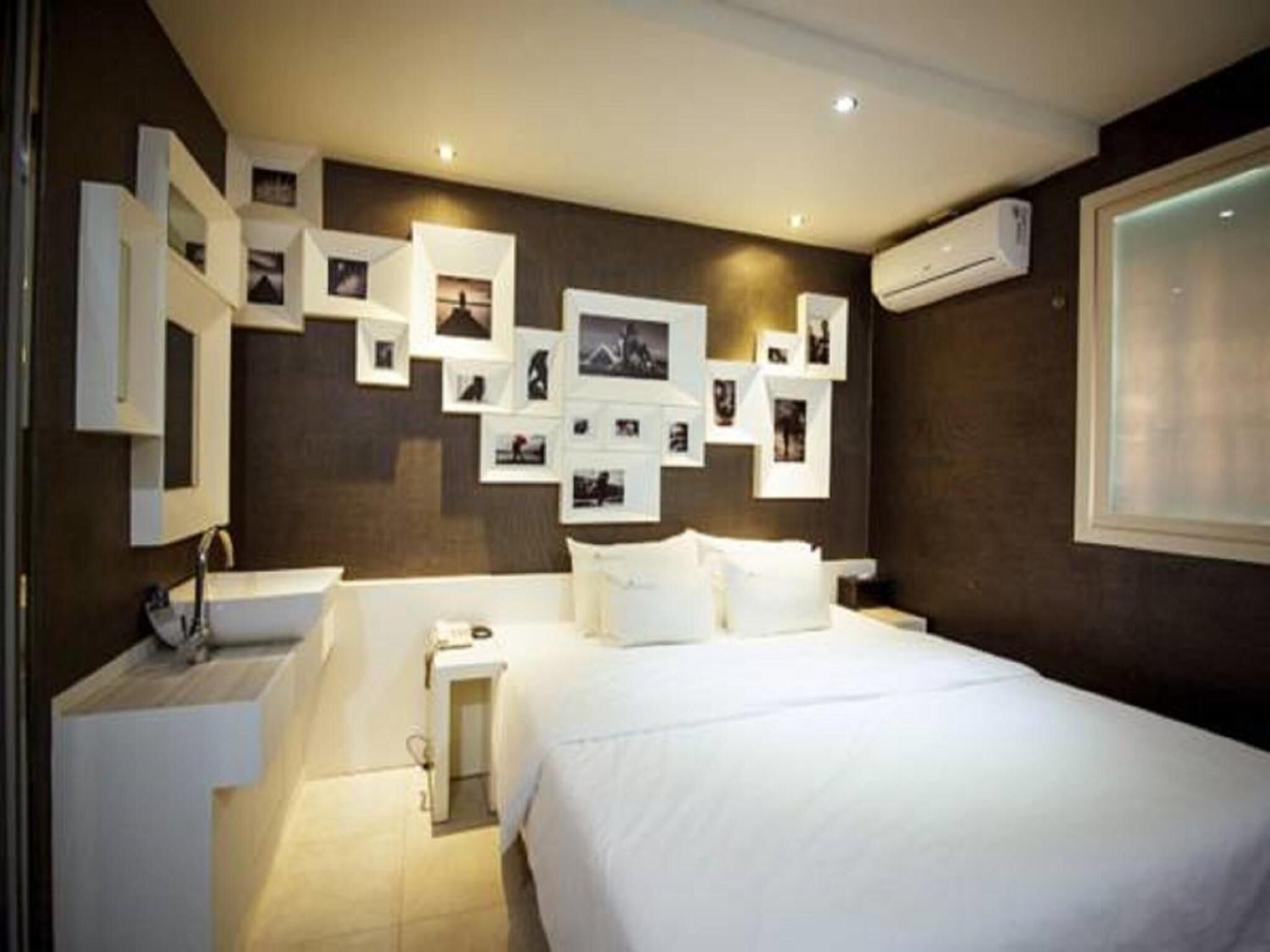 A modern bedroom with a large bed, a built-in desk, and a wall adorned with photographs.