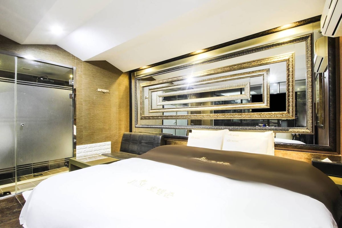 A hotel room with a large bed, a mirror with ornate frames, and a wardrobe.
