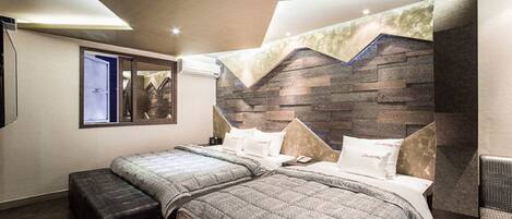 Un dormitorio moderno con dos camas, un ventanal grande y un cabecero con estampado de piedra.