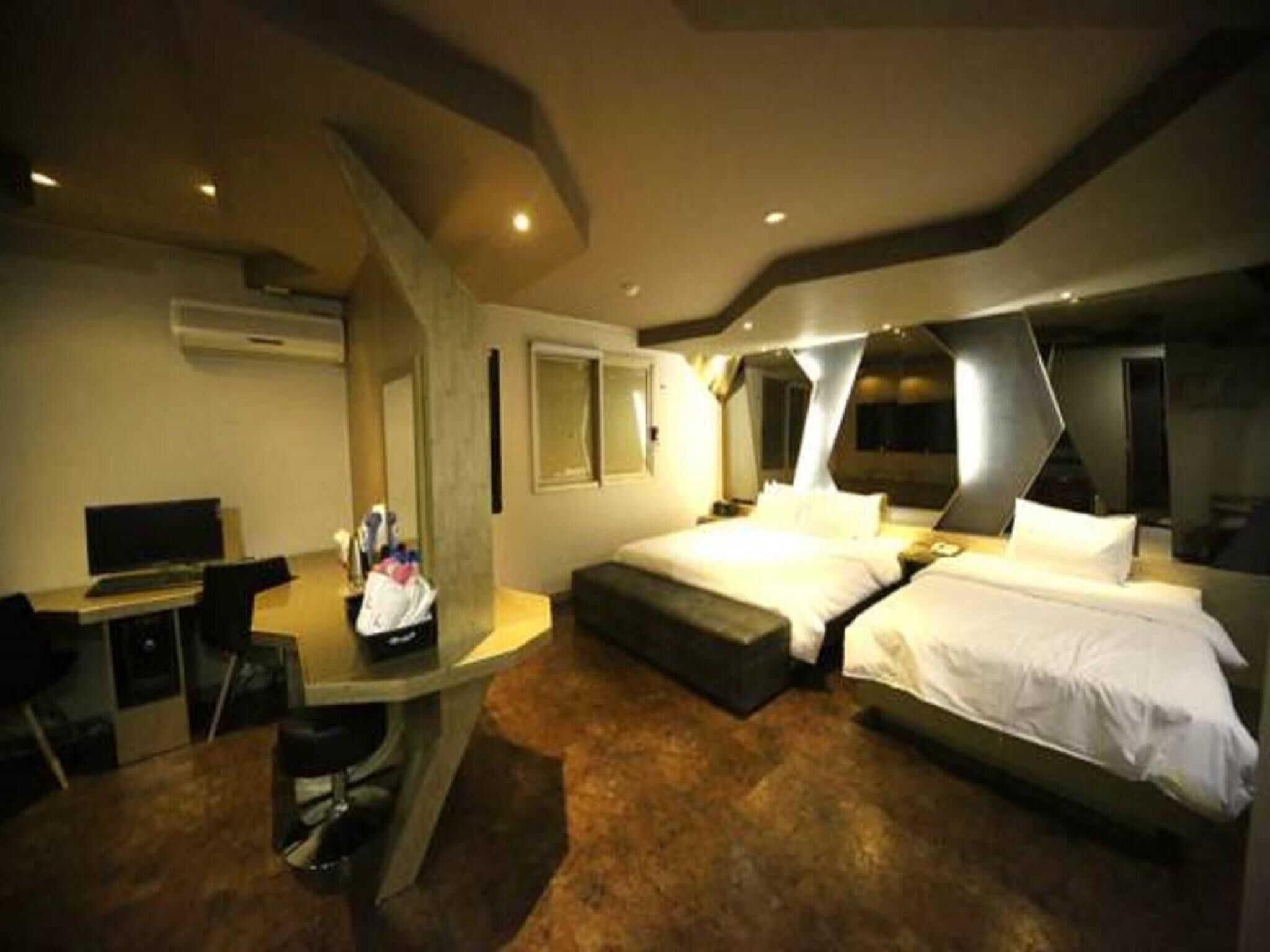 A modern hotel room with a bed, a desk, and a chair.