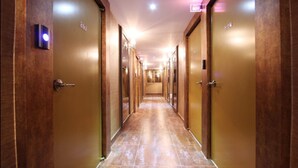 En lang, smal hotellobby med trædøre på begge sider og flisegulv.