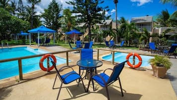 Una piscina al aire libre, sombrillas, tumbonas