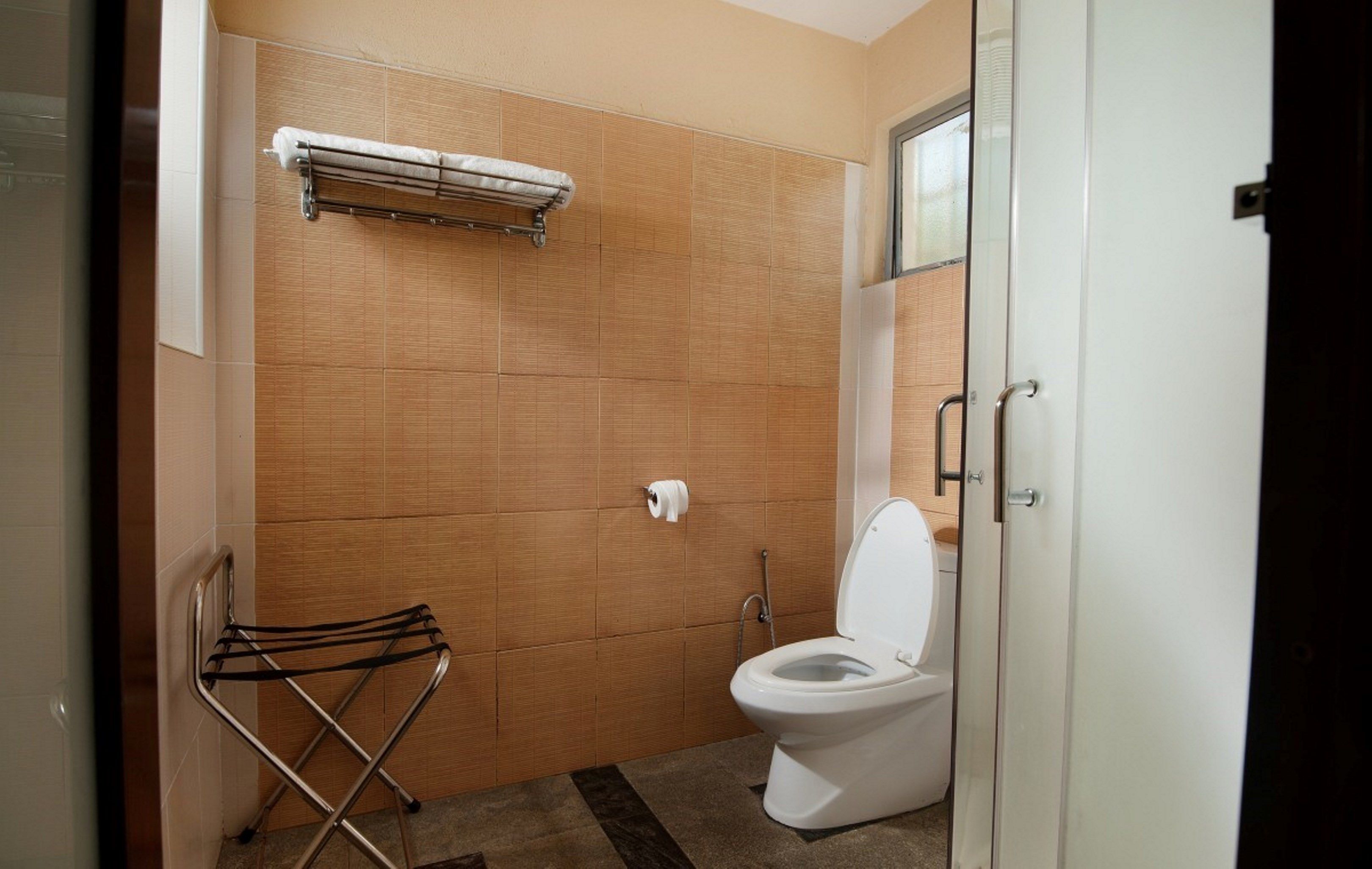 A bathroom with a toilet, a towel rack, and a hand dryer.